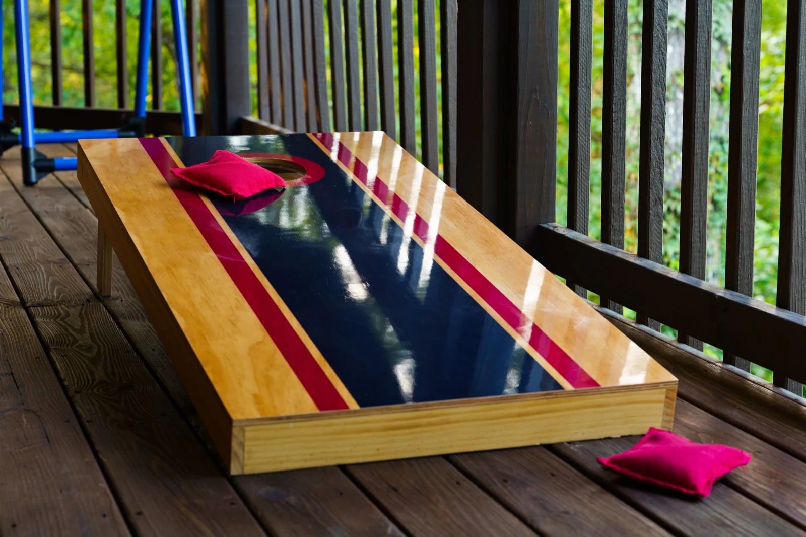 Wooden cornhole board and red beanbags on the covered deck